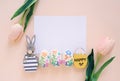 Happy Easter concept with blank card, wooden bunny, colorful easter eggs and pink tulips Royalty Free Stock Photo