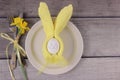 Easter holiday table setting with cutlery on barn boards. Narcissus, bunny from egg and yellow napkin with bow on white