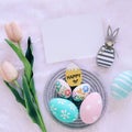 Happy Easter concept with wooden bunny and colorful easter eggs on white fur background and pink tulips Royalty Free Stock Photo