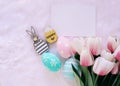 Happy Easter concept with wooden bunny and colorful easter eggs on white fur background and pink tulips Royalty Free Stock Photo