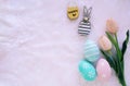 Happy Easter concept with wooden bunny and colorful easter eggs on white fur background and pink tulips Royalty Free Stock Photo