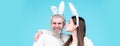 Happy Easter couple kissing, bunny rabbit woman and man hold board paper. Funny Easter bunny couple on blue background