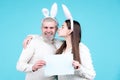 Happy Easter couple kissing, bunny rabbit woman and man hold board paper for text copy space. Funny Easter bunny couple