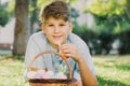 Happy Easter! Cute smiling boy teenager in blue shirt holds basket with handmade colored eggs on grass in spring park. Decoration Royalty Free Stock Photo