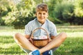 Happy Easter! Cute smiling boy teenager in blue shirt holds basket with handmade colored eggs on grass in spring park. Royalty Free Stock Photo