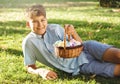 Happy Easter! Cute smiling boy teenager in blue shirt holds basket with handmade colored eggs on grass in spring park. Royalty Free Stock Photo