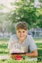 Happy Easter! Cute smiling boy teenager in blue shirt holds basket with handmade colored eggs on grass in spring park. Royalty Free Stock Photo