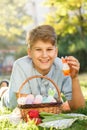 Happy Easter! Cute smiling boy teenager in blue shirt holds basket with handmade colored eggs on grass in spring park. Decoration Royalty Free Stock Photo