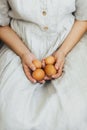 Happy Easter! Easter eggs in hands of woman in rustic linen dress. Aesthetic eco holiday