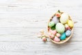 Happy Easter. Easter eggs in basket on colored table with yellow roses. Natural dyed colorful eggs background top view Royalty Free Stock Photo