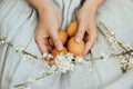 Happy Easter! Easter eggs and spring flowers in hands of woman in rustic linen dress. Aesthetic