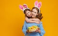 Happy easter! family mother and child daughter with ears hare getting ready for holiday on colored yellow