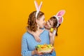 Happy easter! family mother and child daughter with ears hare getting ready for holiday on yellow background Royalty Free Stock Photo