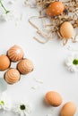 Happy Easter flat lay composition with Easter eggs in straw and spring flowers on white background. Flat lay, top view, vertical