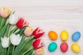 Happy Easter frame border, paschal eggs on a white wood background, bouquet of tulips, floral card, colorful festive template with Royalty Free Stock Photo