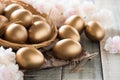 Happy easter! golden of Easter eggs in nest with pink flower and Feather on wooden background