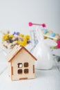Happy Easter greeting card. Miniature wooden house. Rabbits, colorful eggs, spring flowers with tag for text.. Royalty Free Stock Photo
