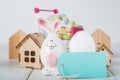 Happy Easter greeting card. Miniature wooden house. Rabbits, colorful eggs, spring flowers with tag for text.. Royalty Free Stock Photo