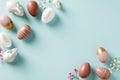 Happy Easter greeting card template. Frame made of Easter eggs, bunnies, flowers on pastel blue background. Flat lay, top view, Royalty Free Stock Photo