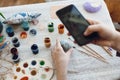 Happy Easter. Hands holding phone and taking photo of stylish easter flat lay of painting egg on rustic table with paint,brushes, Royalty Free Stock Photo