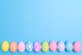 Happy Easter holiday greeting card design concept. Colorful Easter Eggs and spring flowers on blue background. Flat lay, top view Royalty Free Stock Photo