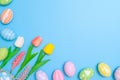 Happy Easter holiday greeting card design concept. Colorful Easter Eggs and spring flowers on blue background. Flat lay, top view Royalty Free Stock Photo