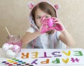 Happy easter. Little girl painter in pink bunny ears with colorful painted eggs. A kid preparing for Easter. Painted hand Royalty Free Stock Photo