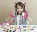 Happy easter little girl painter in pink bunny ears with colorful painted eggs. A kid preparing for Easter. Painted hand Royalty Free Stock Photo