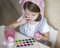 Happy easter little girl painter in pink bunny ears with colorful painted eggs. A kid preparing for Easter. Painted hand Royalty Free Stock Photo