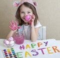 Happy easter little girl painter in pink bunny ears with colorful painted eggs. A kid preparing for Easter. Painted hand Royalty Free Stock Photo