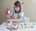 Happy easter little girl painter in pink bunny ears with colorful painted eggs. A kid preparing for Easter. Painted hand Royalty Free Stock Photo