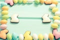 Happy Easter. Pastel color sweet eggs and chocolate rabbits on mint background. Frame. Top view. Copyspace