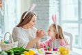 Happy Easter Preparations.Mom and daughter are preparing for Easter together.On the table is a basket with Easter eggs, flowers Royalty Free Stock Photo