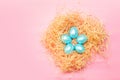 Happy easter simple background, colored pearl blue eggs in hay nest over bright pink