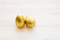 Happy Easter. Stylish easter chocolate eggs in golden foil on white wooden background . Modern easter eggs. Space for text.