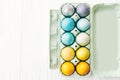 Happy Easter. Stylish Easter eggs in rainbow pastel colors in carton tray on white wooden background, flat lay with space for text