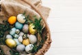 Happy Easter. Stylish easter eggs in rustic basket on white wooden background, top view. Easter hunt concept. Modern easter eggs