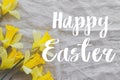 Happy Easter text on beautiful yellow daffodils on rustic linen napkin flat lay, handwritten sign. Beautiful stylish greeting card Royalty Free Stock Photo