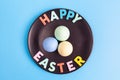 Happy Easter text with colorful eggs arranged on black plate. Royalty Free Stock Photo