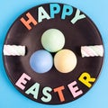 Happy Easter text with colorful eggs and marshmallows arranged on black plate. Royalty Free Stock Photo