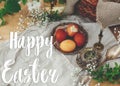 Happy Easter text. Easter greetings lettering. Modern Easter eggs on vintage plate on rustic table with spring flowers,candle, Royalty Free Stock Photo