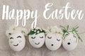 Happy Easter text on eggs with cute funny faces in floral crowns on rustic fabric with spring flowers and blossom, handwritten