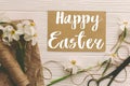 Happy Easter text on greeting card with beautiful daffodils, scissors, twine on rustic wood, flat lay, handwritten sign. Beautiful Royalty Free Stock Photo
