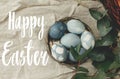 Happy Easter text. Easter greetings lettering. Modern blue Easter eggs on vintage plate on rustic table with spring flowers and Royalty Free Stock Photo