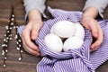 Happy easter. Unpainted eggs in a basket, children`s hands and willow branches on a wooden table.