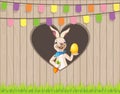 Happy Easter wish you bunny with egg and carrot behind fence on hearth shape hole