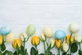 Happy Easter. Yellow and white roses and colored eggs on white wooden background. Easter background with copy space. Floral Royalty Free Stock Photo