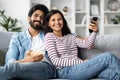 Happy eastern couple watching TV together at home Royalty Free Stock Photo