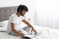 Happy eastern guy studying in bed, using laptop Royalty Free Stock Photo