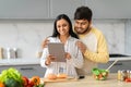 Happy eastern man and woman using tablet white cooking Royalty Free Stock Photo